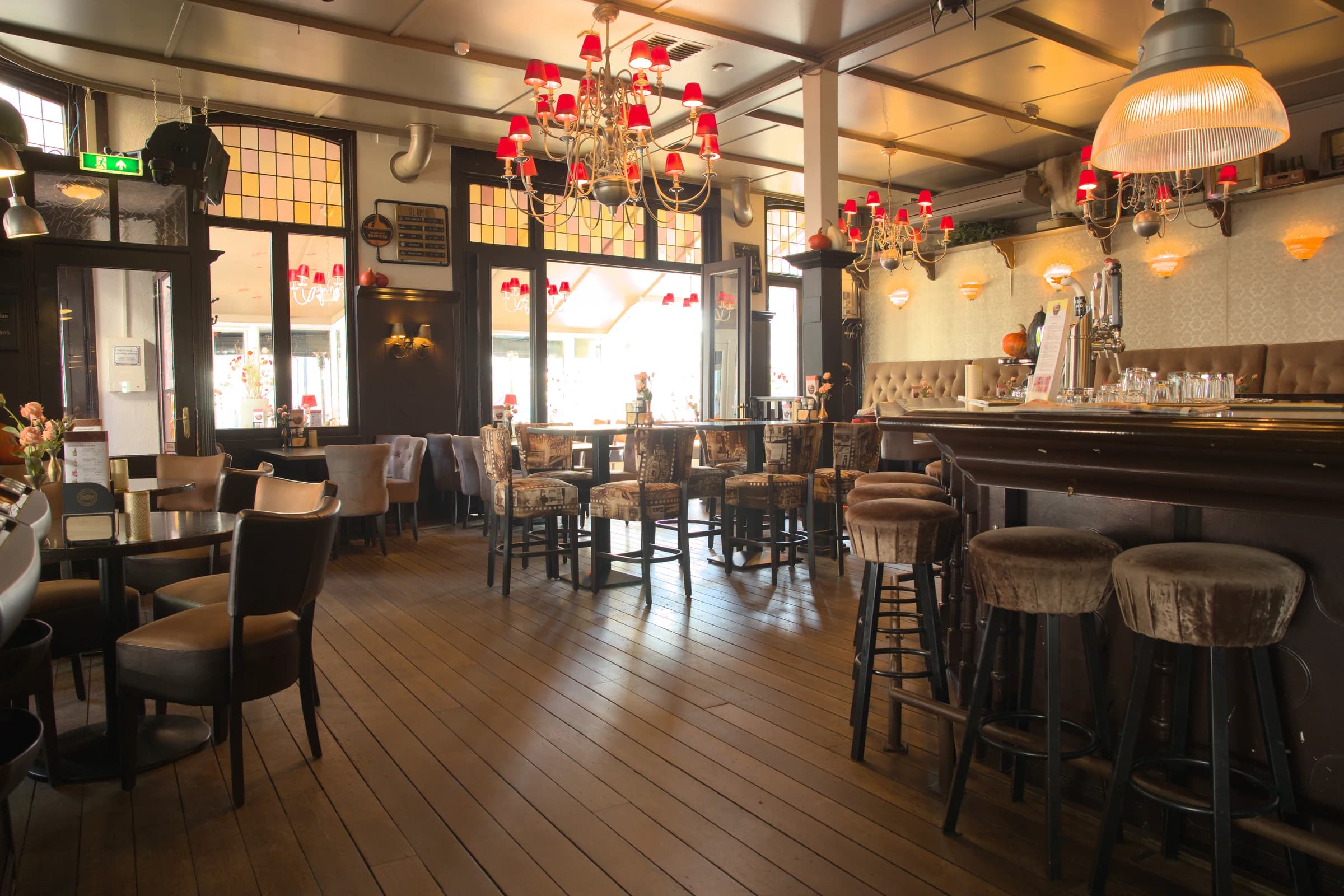 De houten bar en hoge tafels onder de rode kroonluchters